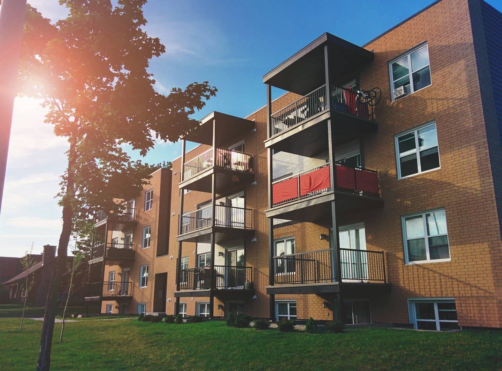 Brick apartment building with stacked steel balconies in warm evening light
