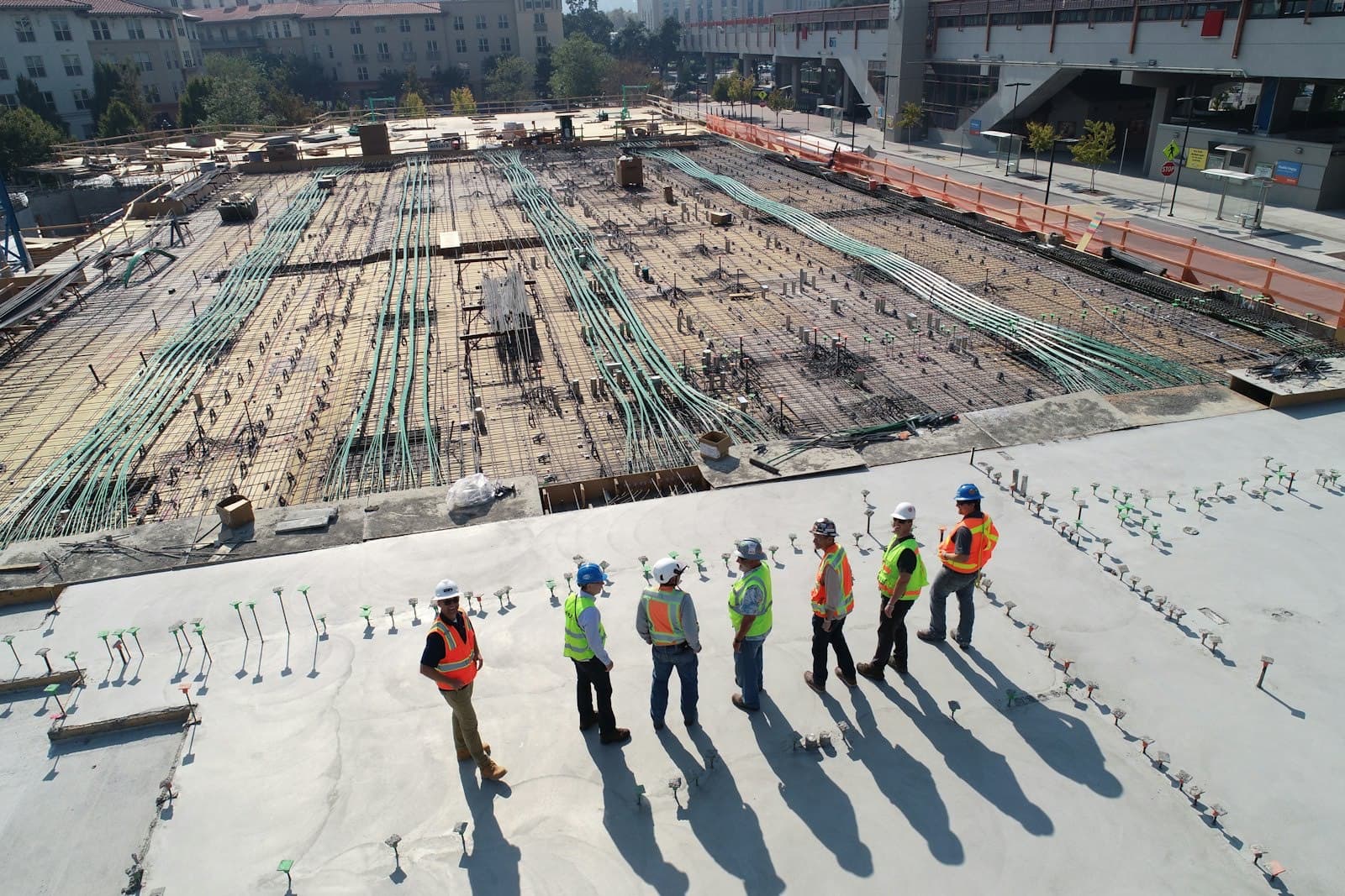 Engineers in hard hats reviewing a foundation site with exposed reinforcement